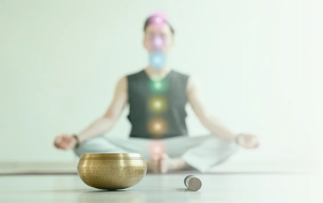 Personne en tailleur derrière un bol tibétain